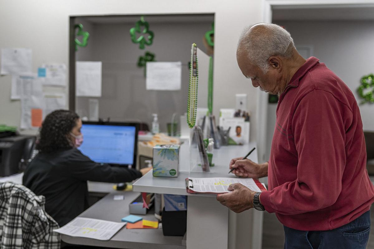 Patient standing at reception desk and completing paperwork at medical appointment